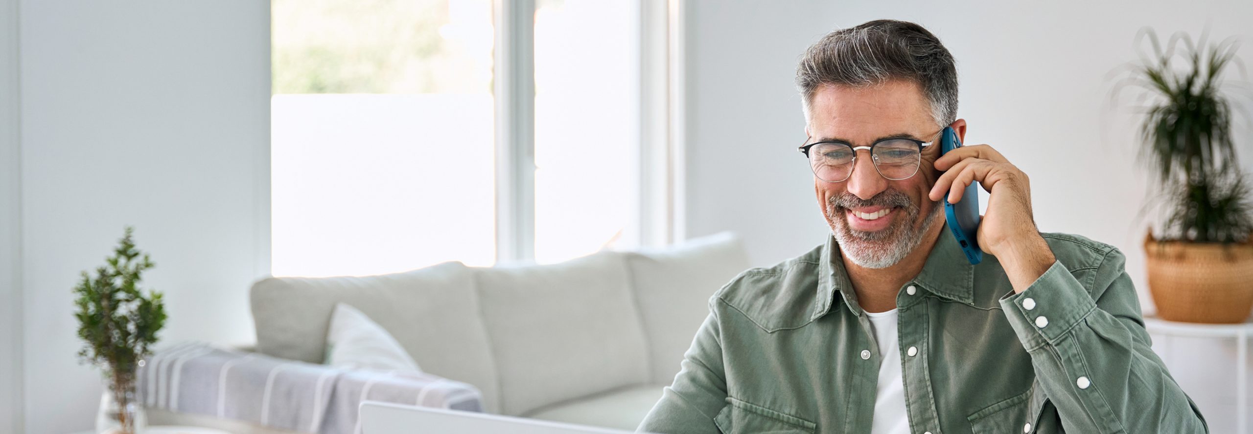 Mann mit Smartphone am Laptop